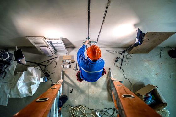 Electrician working overhead in industrial space